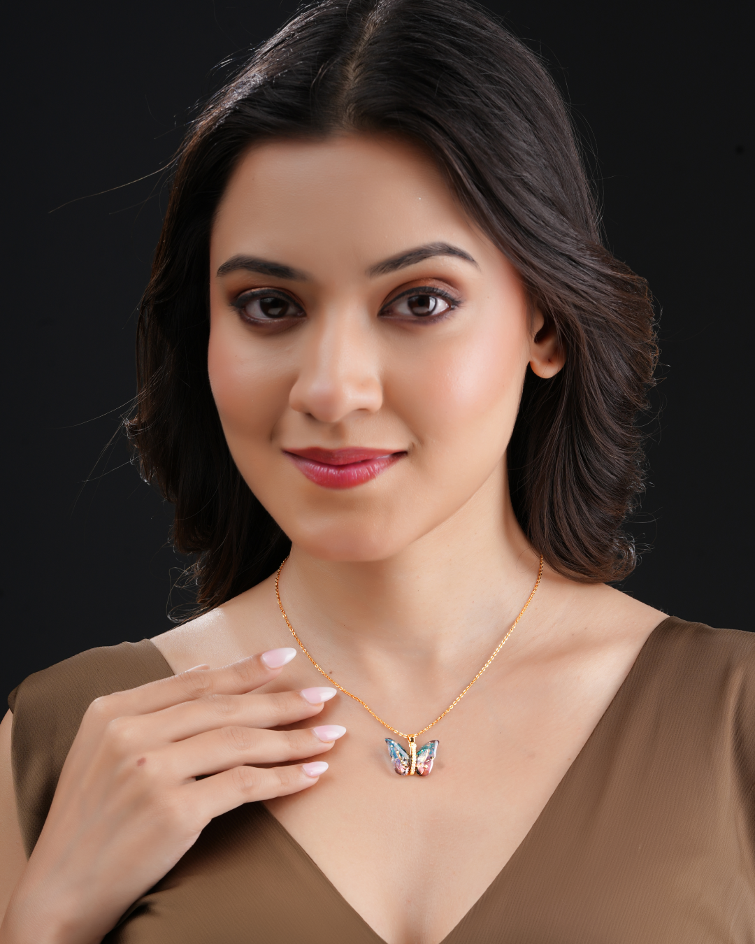 Woman wearing elegant butterfly crystal pendant necklace with gold-tone chain.