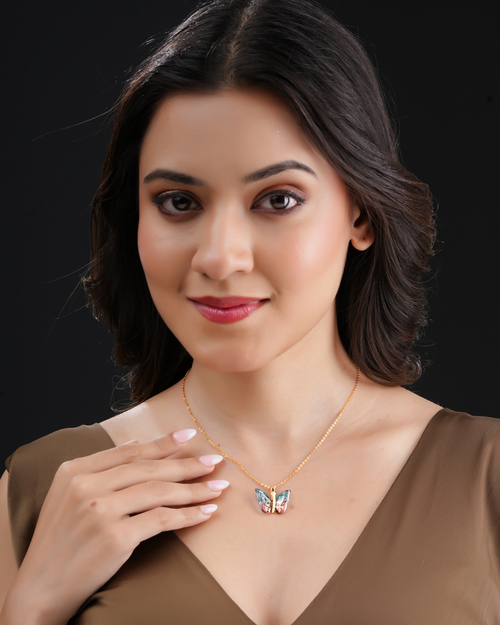 Woman wearing elegant butterfly crystal pendant necklace with gold-tone chain.